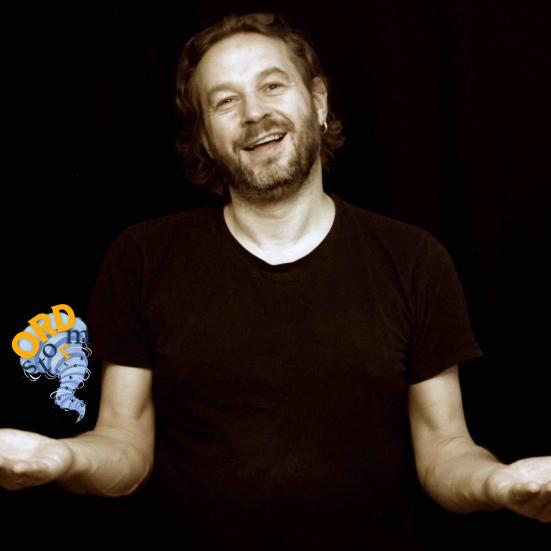 En mand står på en mørk baggrund og fortæller.