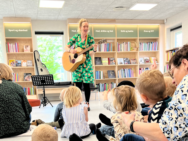 En kvinde med en guitar foran en gruppe børn