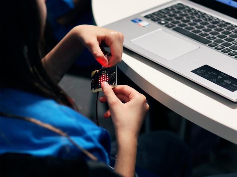 Et foto af hænder, der sidder men den chip foran en computer.