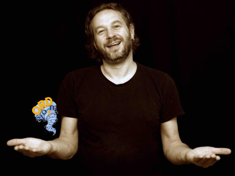 En mand står på en mørk baggrund og fortæller.