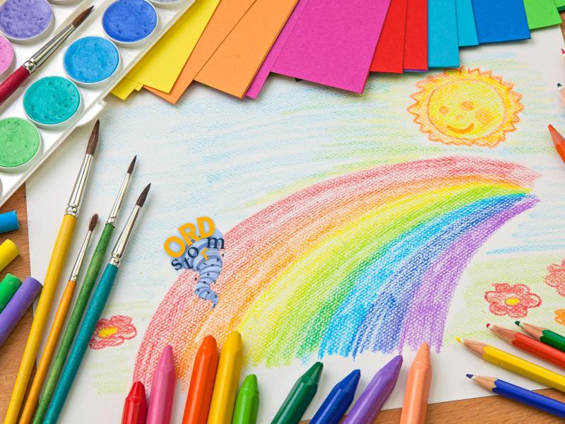 En tegning med pensler, farvekridt og forskelligt papir. 