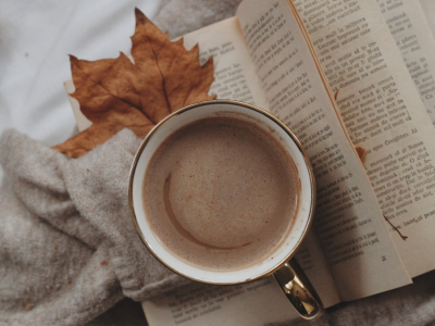 Efterårshygge med bog, tæppe og en kop kaffe
