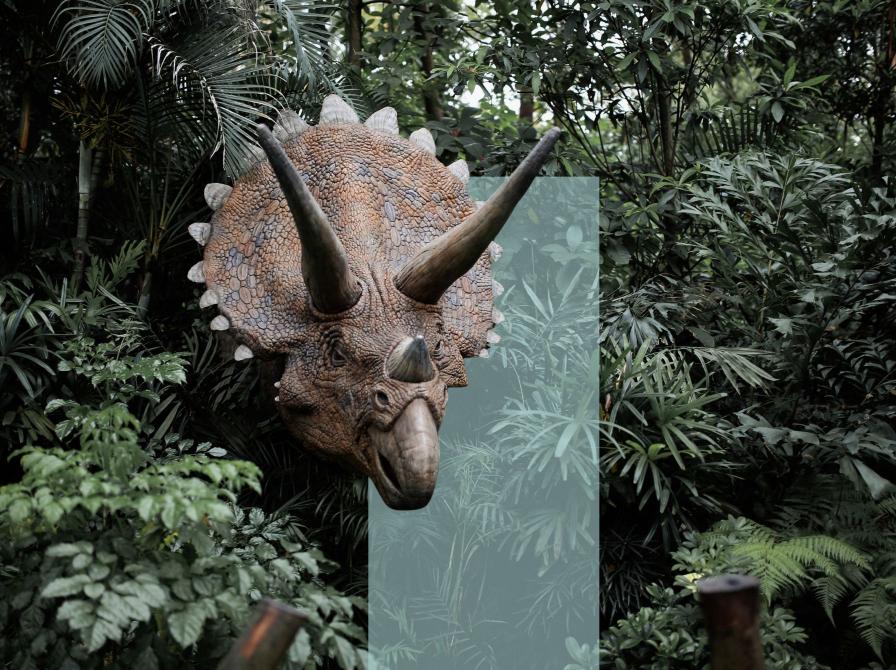 En hornet dinosaur stikker hovedet frem mellem tæt, grøn jungle.